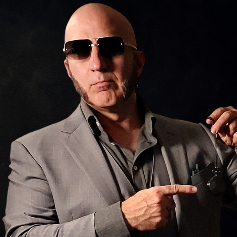 Faggot brainwashing Master, The Shadow Priest, in a grey suit, pointing at a pocketwatch